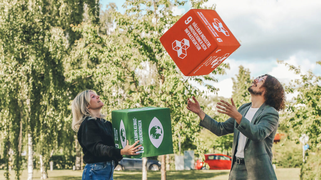 En kvinna och en man kastar kuber som representerar de globala hållbarhetsmålen.