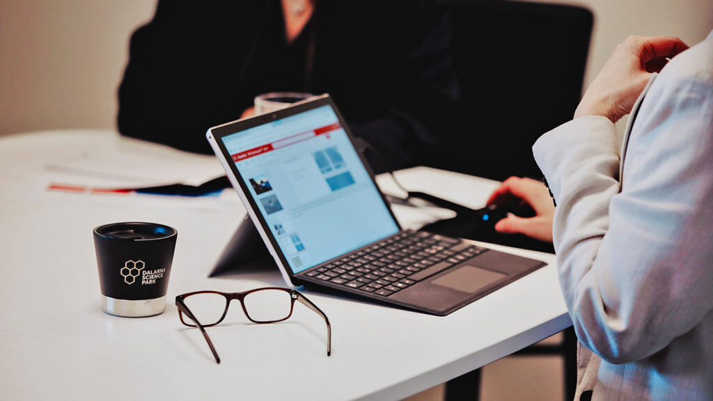 Uppfälld laptop på ett skrivbord med glasögon brevid.