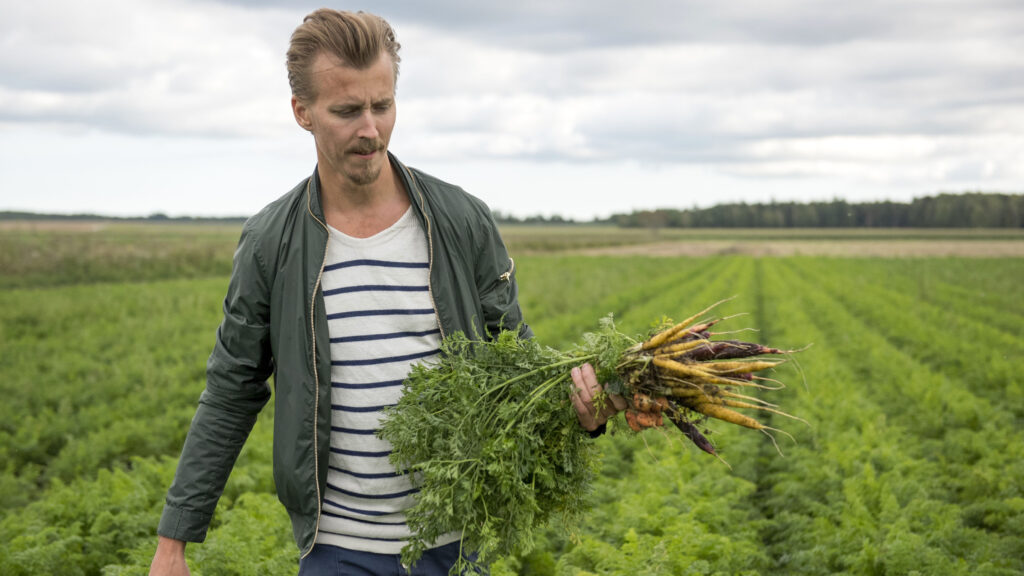Paul Svensson håller i en knippe morötter utomhus