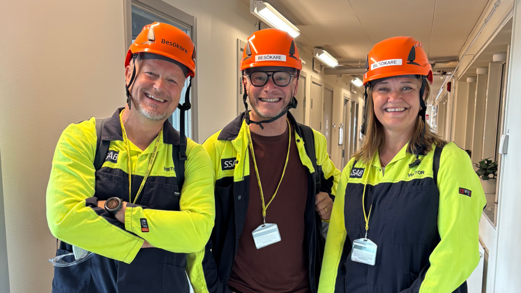 Tre personer med varselkläder och orange hjälmar.